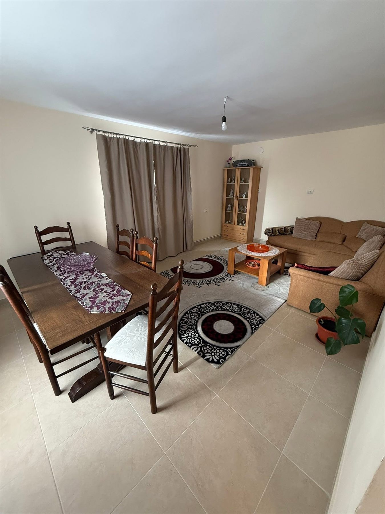 Sala de mese și zona de living, cu masă lungă din lemn și canapea
